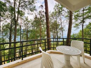 a table and chairs on a balcony with trees at Hotel Bliss in Kasauli