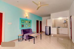 a living room with a couch and a table and a chair at Vrishi Suites in Bangalore