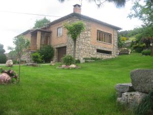 オヨス・デル・エスピーノにあるLa Laderaの緑の芝生のある庭の石造りの家