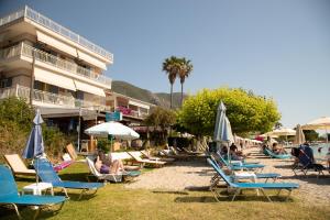 eine Gruppe von Stühlen und Sonnenschirmen am Strand in der Unterkunft Hotel Nydri Beach in Nydri