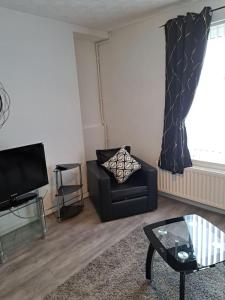 a living room with a chair and a television at 1 Bed Apart in Dowlais