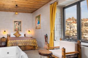 a bedroom with a bed and a tub and a window at Cappadocia hotel Megaron cave in Ortahisar