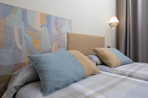 a bedroom with two beds with pillows and a painting at Hotel de Montaña El Mirador in Broto