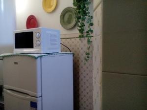 a microwave on top of a refrigerator in a kitchen at Residência Matos Pereira in Vila Real de Santo António