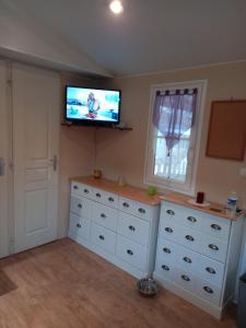 1 dormitorio con cómoda blanca y TV de pantalla plana en Mobil-home camping, 