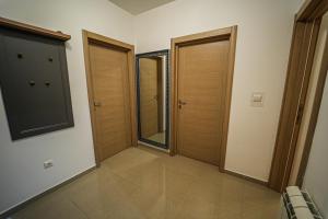 a hallway with two wooden doors in a room at URBAN GREY APARTMAN in Sremska Mitrovica