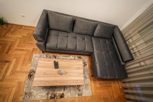 a black leather couch in a living room with a coffee table at URBAN GREY APARTMAN in Sremska Mitrovica