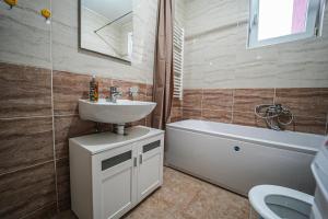 a bathroom with a sink and a tub and a toilet at URBAN GREY APARTMAN in Sremska Mitrovica