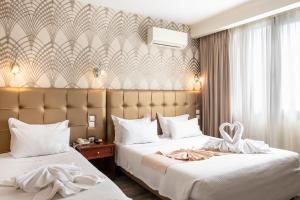 Habitación de hotel con 2 camas con sábanas blancas en Athens Golden City Hotel, en Atenas