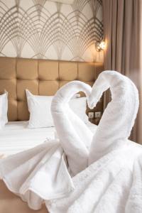 Una cama con dos cisnes blancos haciendo un corazón en Athens Golden City Hotel en Athens
