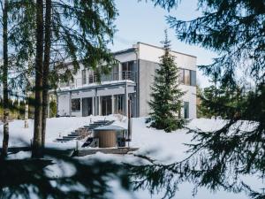 una casa nella neve con alberi in primo piano di Villa Saskia a Otepää