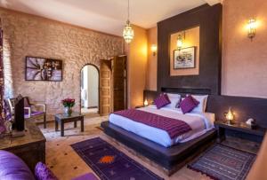 a bedroom with a large bed with purple pillows at Charmante Villa Riad Dharma in Essaouira