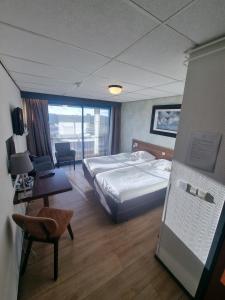 a hotel room with a bed and a desk and a room with a bed at Eemshotel in Delfzijl