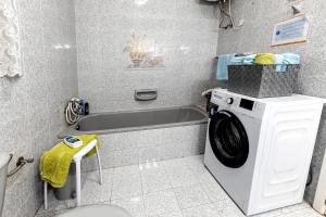 a bathroom with a washing machine and a bath tub at Seaside Flat with Scenic Country Views in Mellieħa