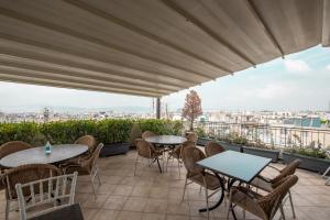 a patio with tables and chairs and a view of the city at Athens Golden City Hotel in Athens