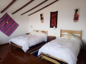 two beds in a room with white sheets at Hostal Inca Uma in Comunidad Yumani