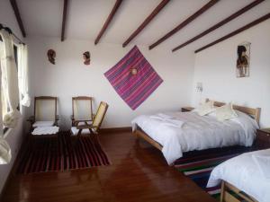 a bedroom with two beds and two chairs at Hostal Inca Uma in Comunidad Yumani
