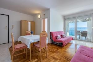 uma sala de estar com uma mesa e uma cadeira rosa em Pasalic Novi em Novi Vinodolski