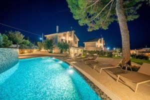 a swimming pool with chairs and a house at night at Seashell Luxury Residence in Lixouri