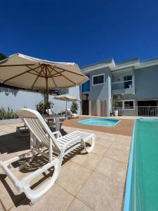 a pair of chairs and an umbrella next to a swimming pool at Hotel Pousada Mar Azul in Itapoa