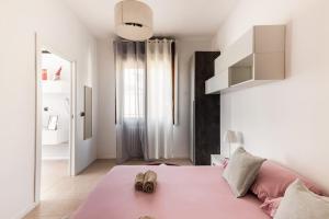 um quarto com uma cama rosa com sapatos em “Casa Moderna con parcheggio privato” em Imola