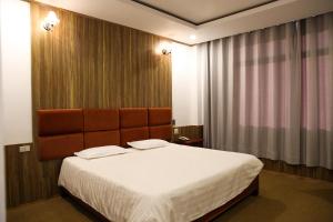 um quarto com uma cama grande e uma janela grande em Mittaphap Hotel Oudomxai em Muang Xai