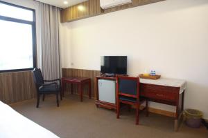 a room with a desk with two chairs and a television at Mittaphap Hotel Oudomxai in Muang Xai