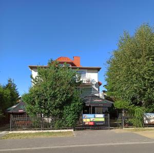 a building with a fence and trees in front of it at Bursztyn in Rewal