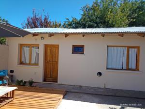 ein kleines weißes Haus mit einer Holzterrasse in der Unterkunft LIBERATA in Esquel