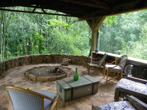 a patio with chairs and a fire pit in the woods at KLIPINNIBOS Nature Farm in Schoemanskloof