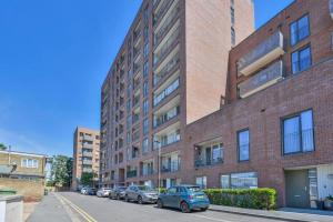 a brick building with cars parked in front of it at Canning Town 2 Bed Apartment in London