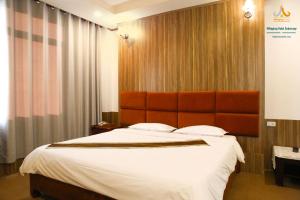 Mittaphap Hotel Oudomxai في موانج إكساي: غرفة نوم بسرير كبير مع اللوح الأمامي كبير