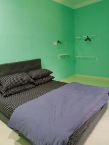 a bedroom with a large bed with green walls at Makmur Homestay Marang in Marang
