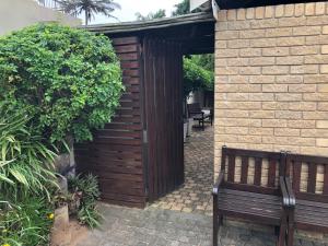 a wooden bench sitting in front of a brick wall at 8 Ocean Drive Self Catering Unit in Ballito