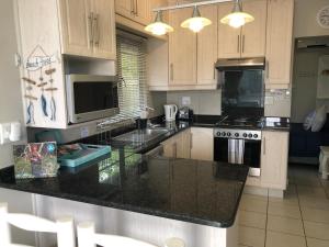 a kitchen with wooden cabinets and a black counter top at 8 Ocean Drive Self Catering Unit in Ballito