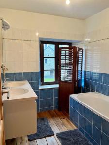 een blauwe en witte badkamer met een bad en een wastafel bij Charmante maison de caractère à 2Km de Redu in Libin