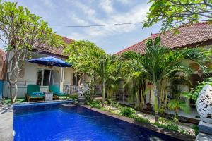 a swimming pool in front of a house with palm trees at Naturale Guest House in Nusa Lembongan