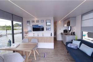 a kitchen and a living room with a table and a couch at Hausboot Fjord Dory mit Biosauna in Schleswig in Schleswig