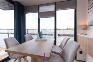 ein Esszimmer mit einem Tisch, Stühlen und Fenstern in der Unterkunft Hausboot Fjord Dory mit Biosauna in Schleswig in Schleswig
