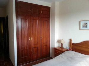 een slaapkamer met een grote houten kast en een bed bij Enjoy Life Chipiona in Chipiona +33 foto's