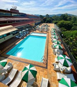 ein großer Pool mit Sonnenschirmen und Liegestühlen in der Unterkunft Hotel Cabreúva Resort in Cabreúva
