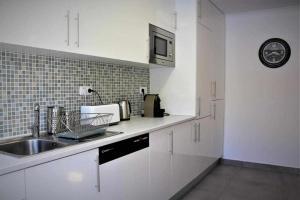 a white kitchen with a sink and a microwave at AlgarveSand Carvoeiro in Carvoeiro