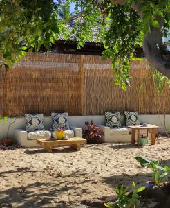 um sofá com almofadas e mesas num quintal em Philoxenia, maison et table d'hôtes em La Saline-Les-Bains