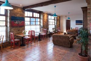 a living room with tables and chairs and a brick wall at Hotel Restaurante Cabo Vidío in Oviñana