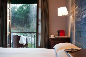 a bedroom with a bed and a window with a balcony at Hotel Gastronómico Cabo Vidío in Oviñana