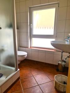 a bathroom with a toilet and a sink and a window at Gästehaus Zum Weinbauer in Rhodt unter Rietburg