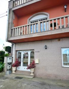 een huis met een balkon en een deur en bloemen bij Apartamentos Caleiro 4P - Vilanova de Arousa in Villanueva de Arosa
