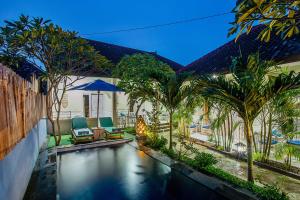 a swimming pool with chairs and palm trees in a house at Naturale Guest House in Nusa Lembongan