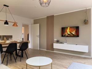 a living room with a table and a tv on the wall at Ferienhaus Bodensee - by Heinke Wohnraum in Oberteuringen