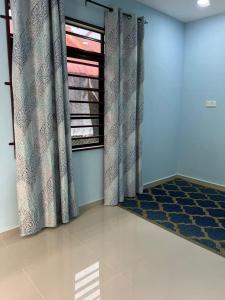 Makmur Homestay Marang في مارانغ: غرفة مع نافذة مع ستائر وسجادة